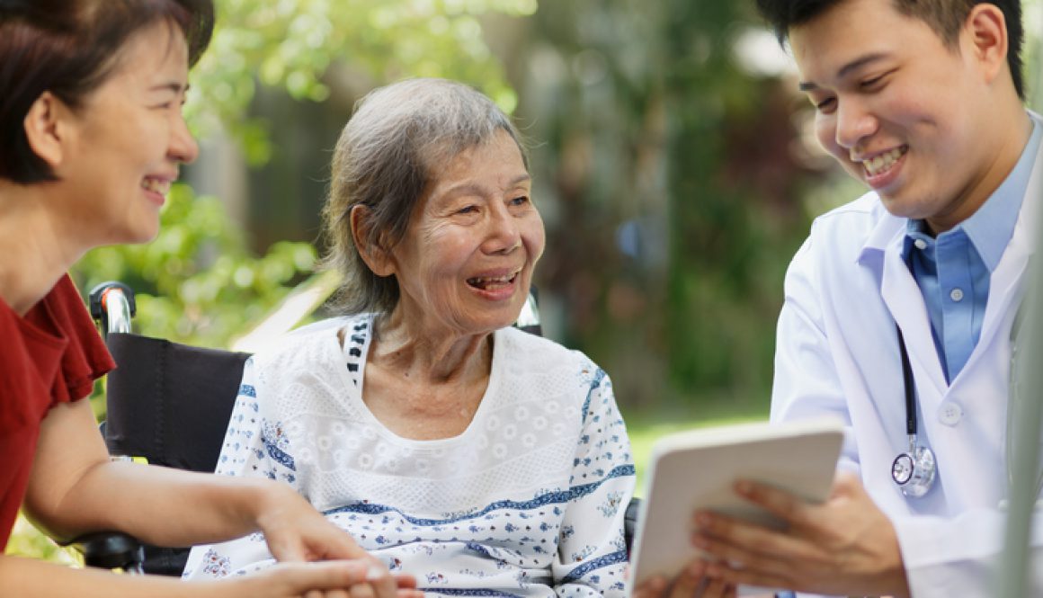 Asian doctor talking with elderly female patient on wheelchair